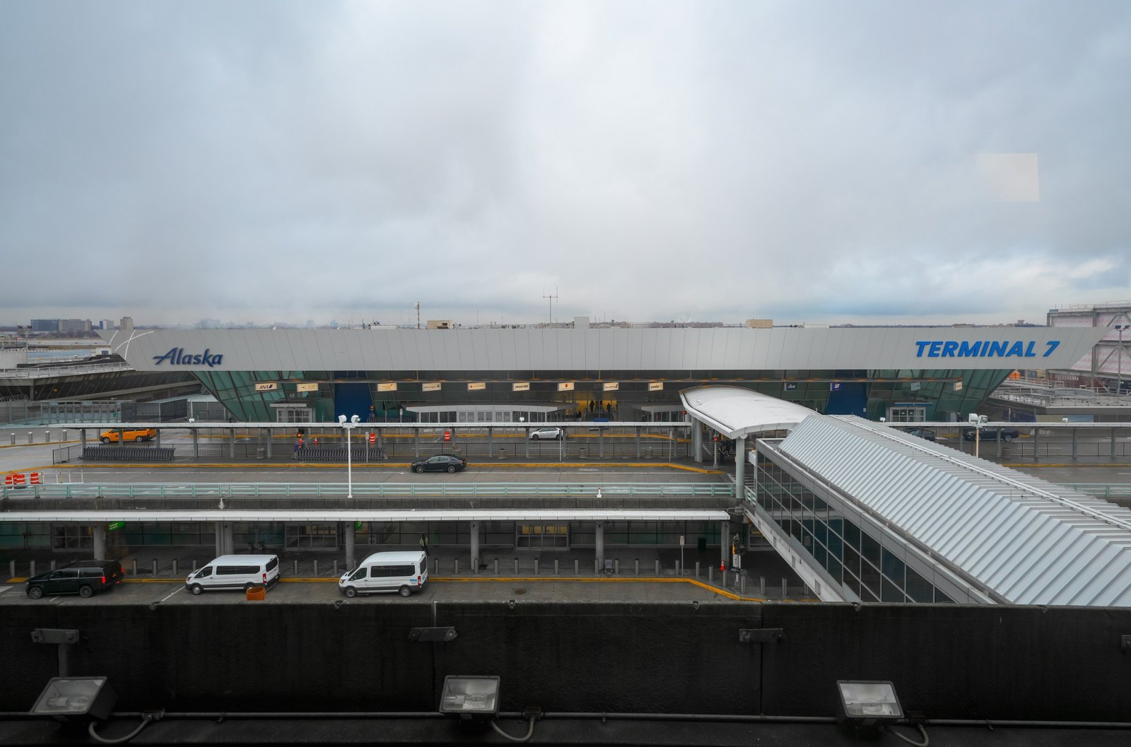Exterior photograph of the JFK Terminal 7 departures level with the roadway and Alaska Airlines signage